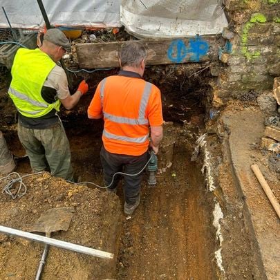 Groundworkers installing pipework in an excavated trench