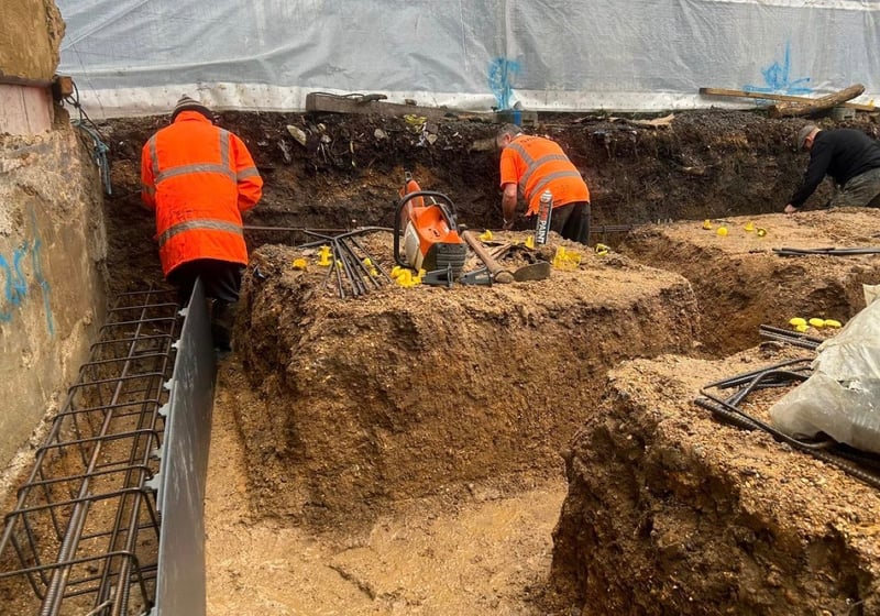 Groundworkers installing a reinforced concrete foundation in a deep excavation